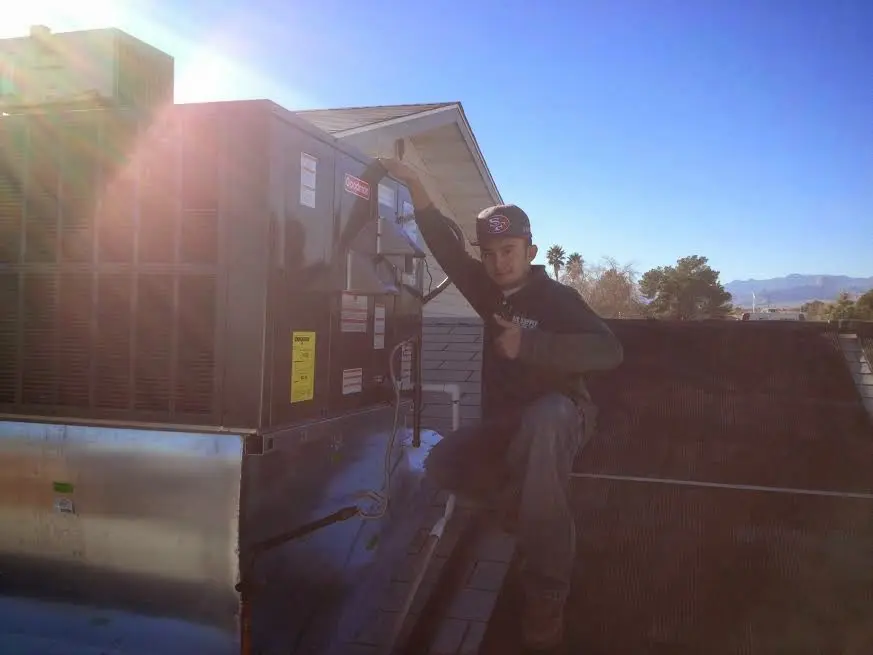HVAC technician performing AC Tune-Up on a rooftop unit in Reserve